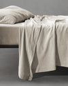 Society Limonta Smir flat sheet in Mastice beige draping over a bed, highlighting the warm, soft-washed winter texture.
