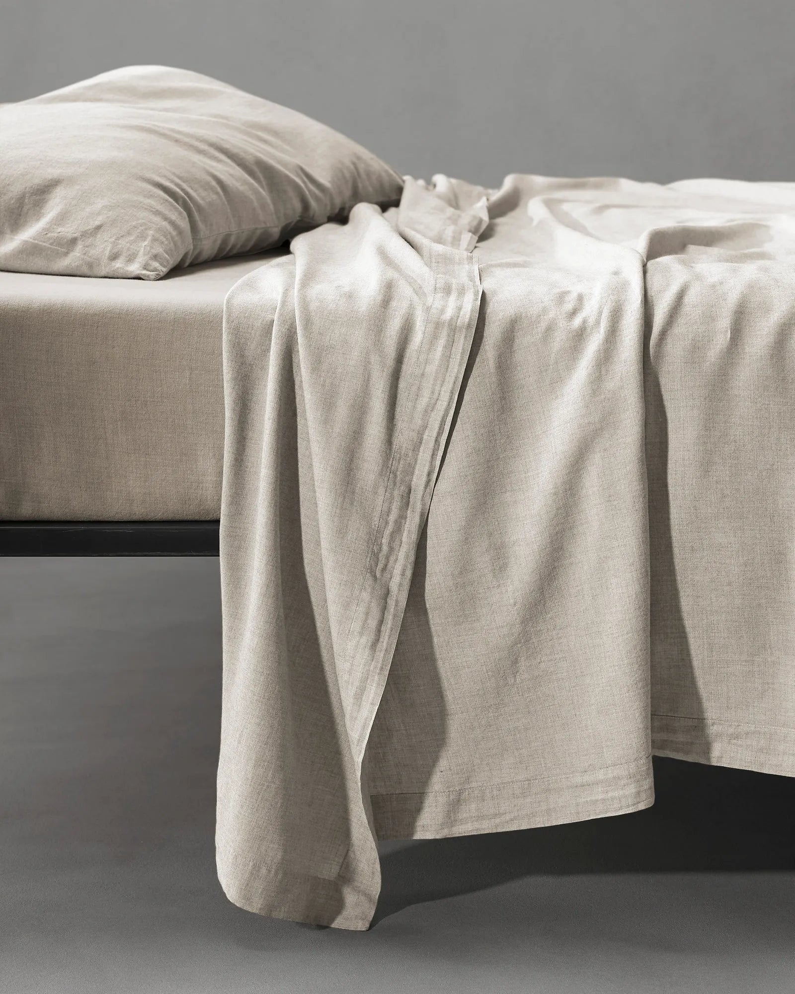 Society Limonta Smir flat sheet in Mastice beige draping over a bed, highlighting the warm, soft-washed winter texture.