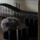 Senufo Ottoman featuring Black African Walnut and Sheep Wool, designed by Arno DeClercq in a stylish interior setting.