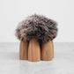 Senufo Ottoman by Arno DeClercq, featuring Black African Walnut base and plush Sheep Wool top for unique seating.
