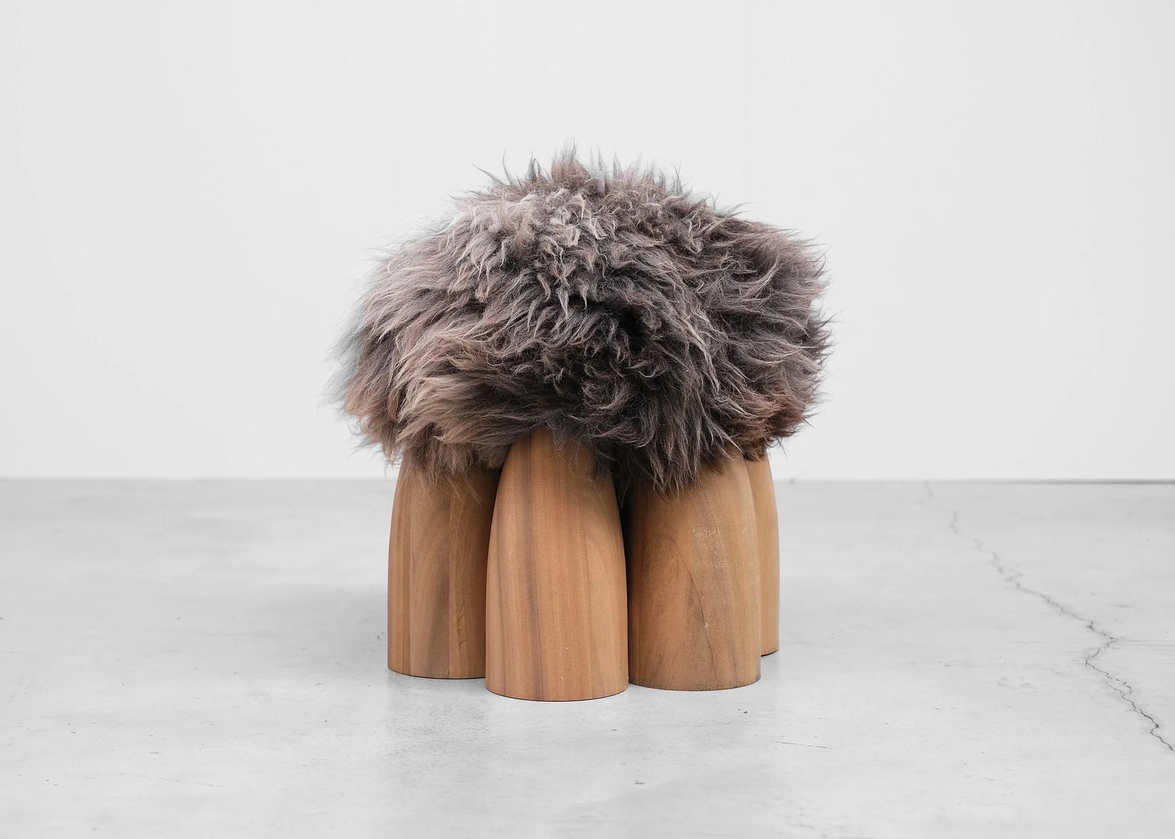 Senufo Ottoman by Arno DeClercq, featuring Black African Walnut base and plush Sheep Wool top for unique seating.