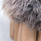 Senufo Ottoman featuring a soft sheep wool seat and sculptural Black African Walnut legs by Arno DeClercq.