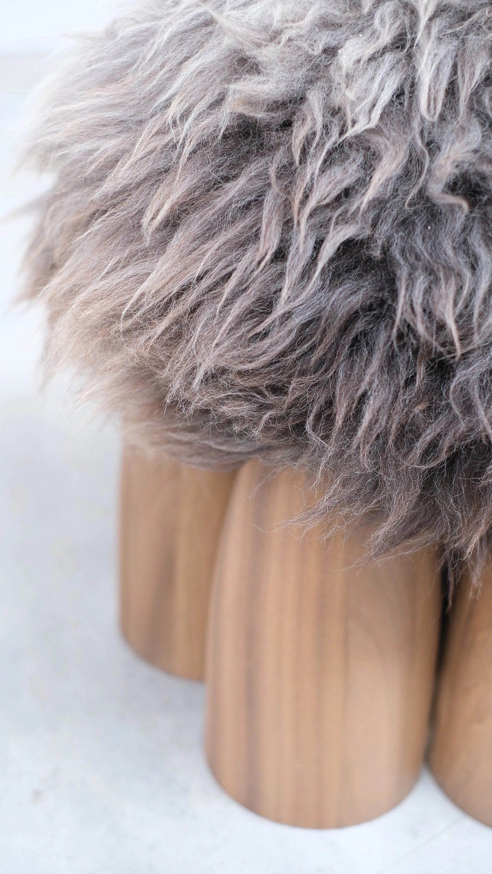 Senufo Ottoman featuring a soft sheep wool seat and sculptural Black African Walnut legs by Arno DeClercq.