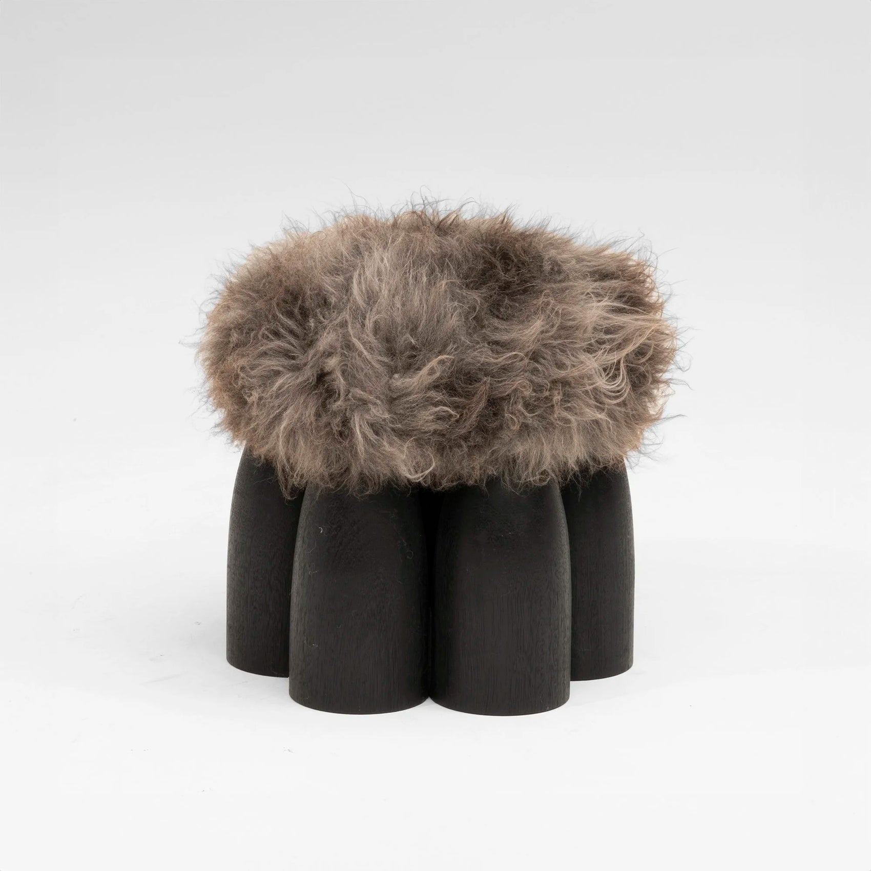Senufo Ottoman by Arno DeClercq featuring Black African Walnut and Sheep Wool for a sculptural seating experience.