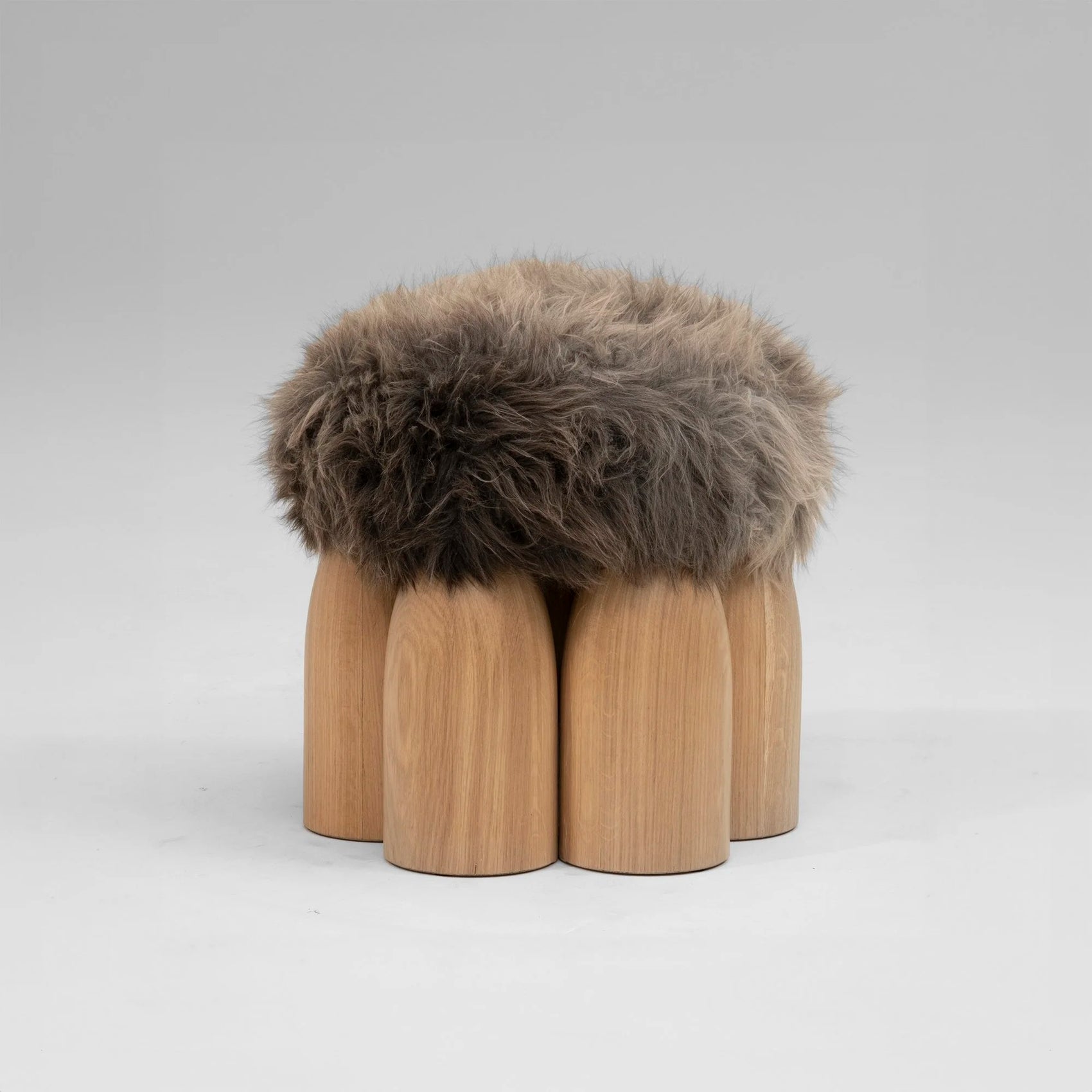 Senufo Ottoman by Arno DeClercq with Black African Walnut base and Sheep Wool cushion, showcasing unique sculptural design.