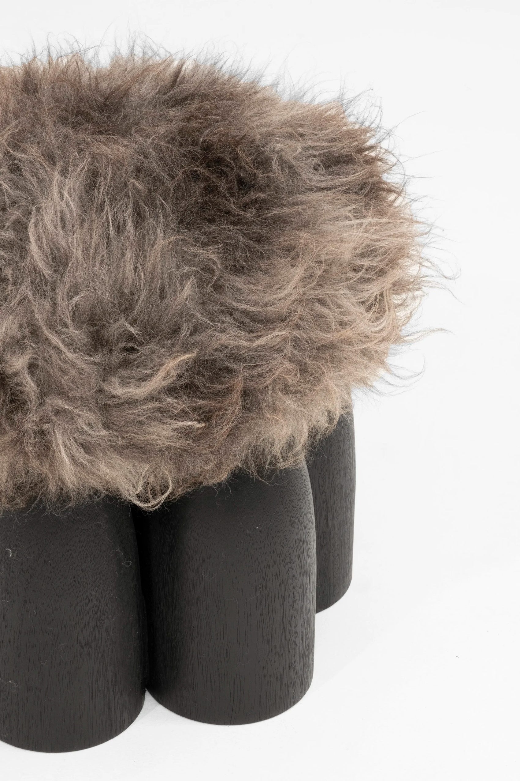 Senufo Ottoman featuring a plush sheep wool top and a sculptural base made of Black African Walnut.