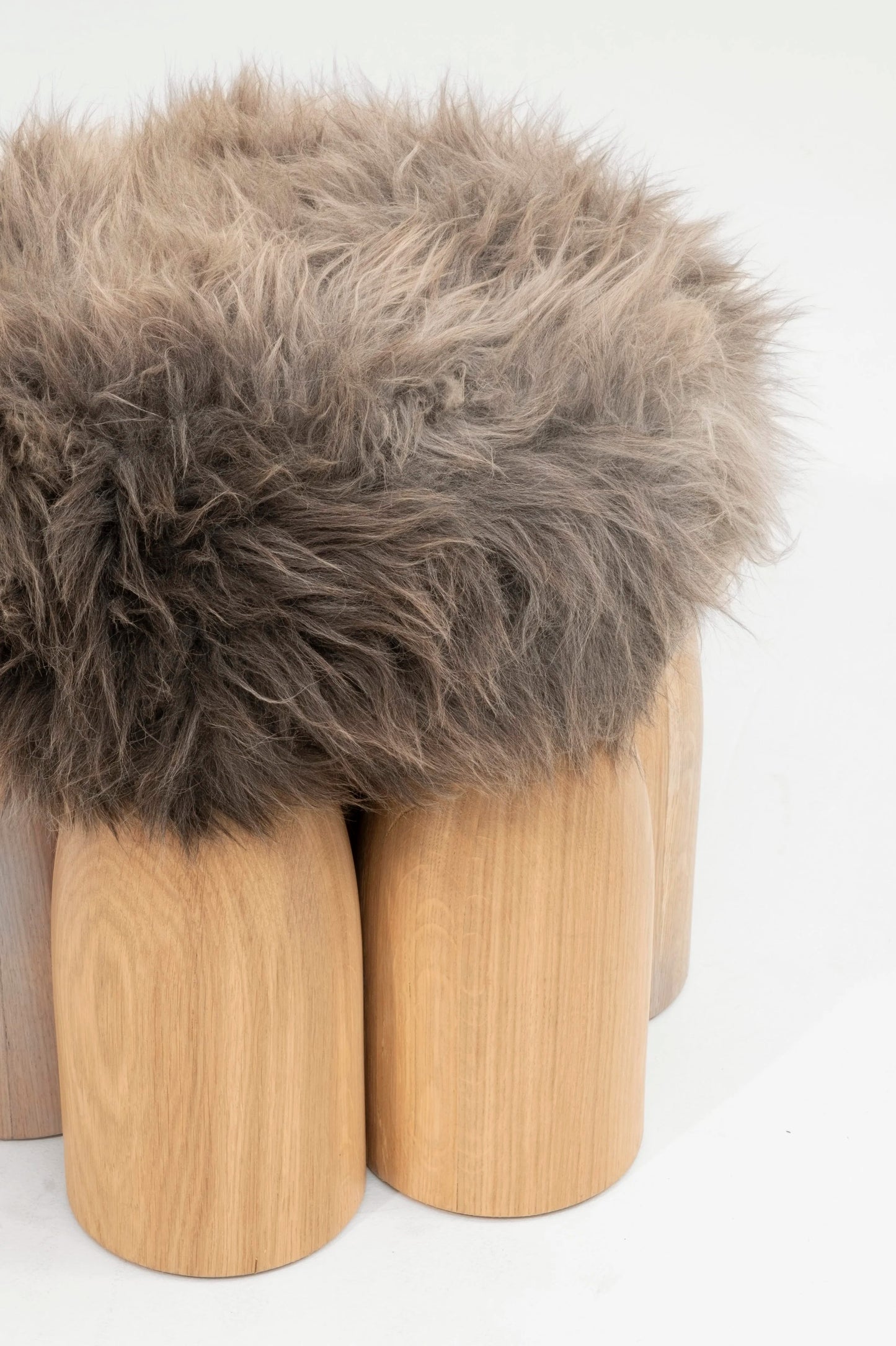 Senufo Ottoman featuring a plush sheep wool top and rounded Black African Walnut legs, designed by Arno DeClercq.