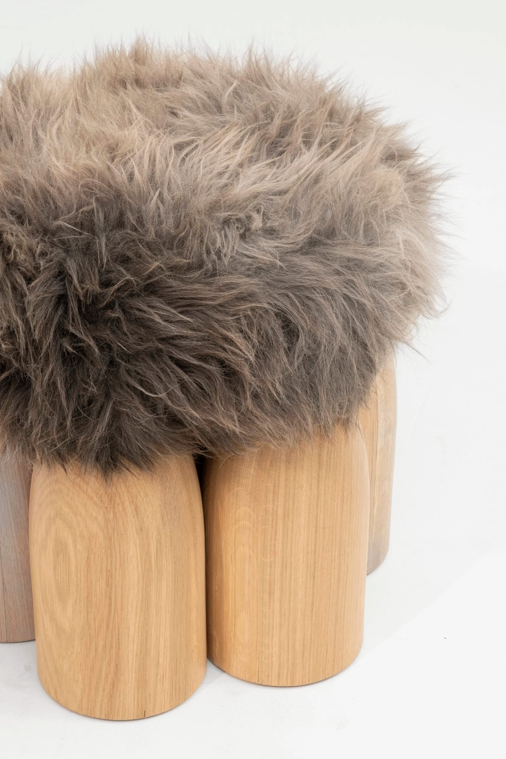 Senufo Ottoman featuring a plush sheep wool top and rounded Black African Walnut legs, designed by Arno DeClercq.