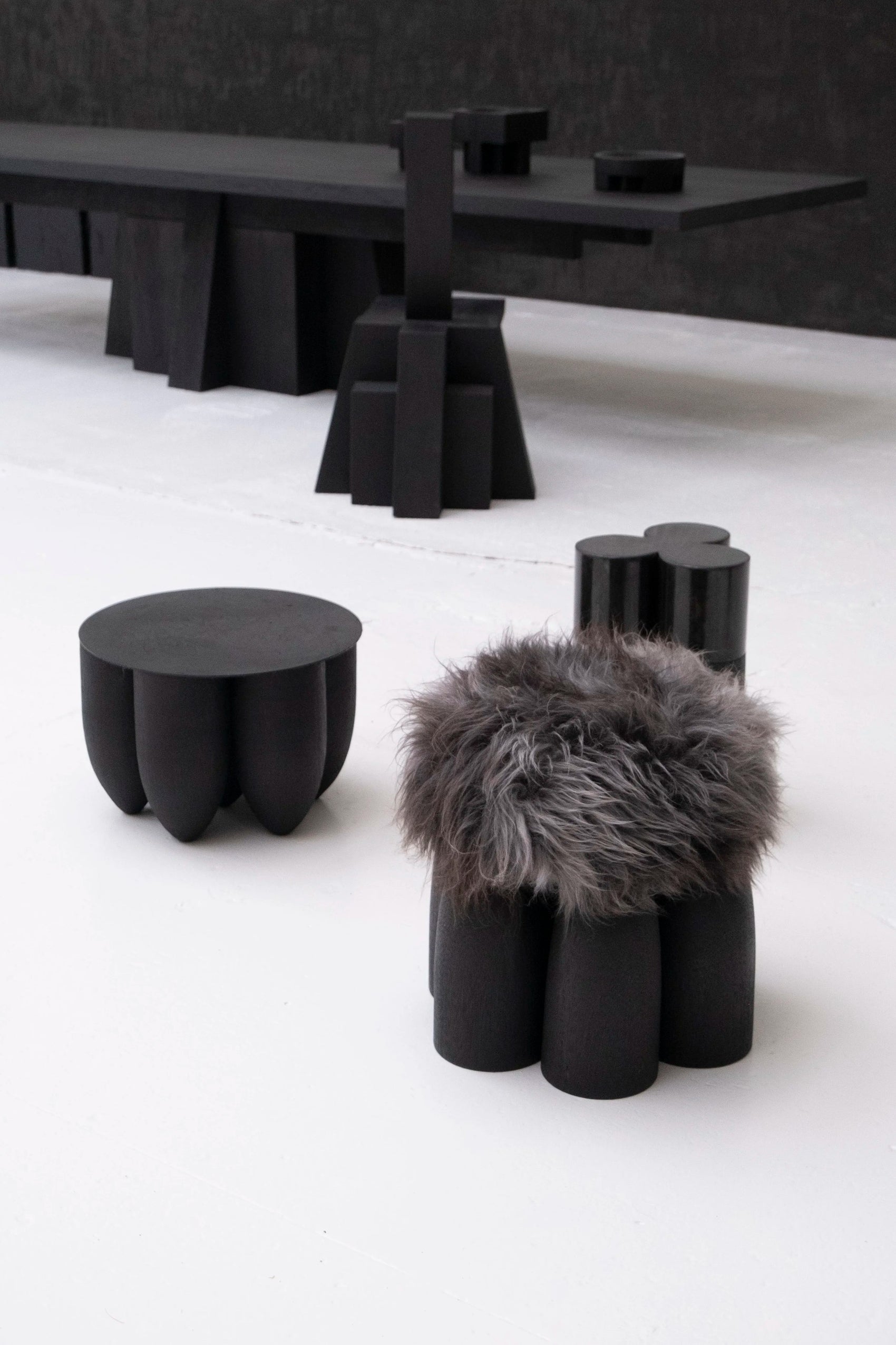 Senufo Ottoman by Arno DeClercq features Black African Walnut base and Sheep Wool for a sculptural seating experience.