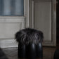 Senufo Ottoman by Arno DeClercq with Black African Walnut base and Sheep Wool seat in an elegant interior setting.