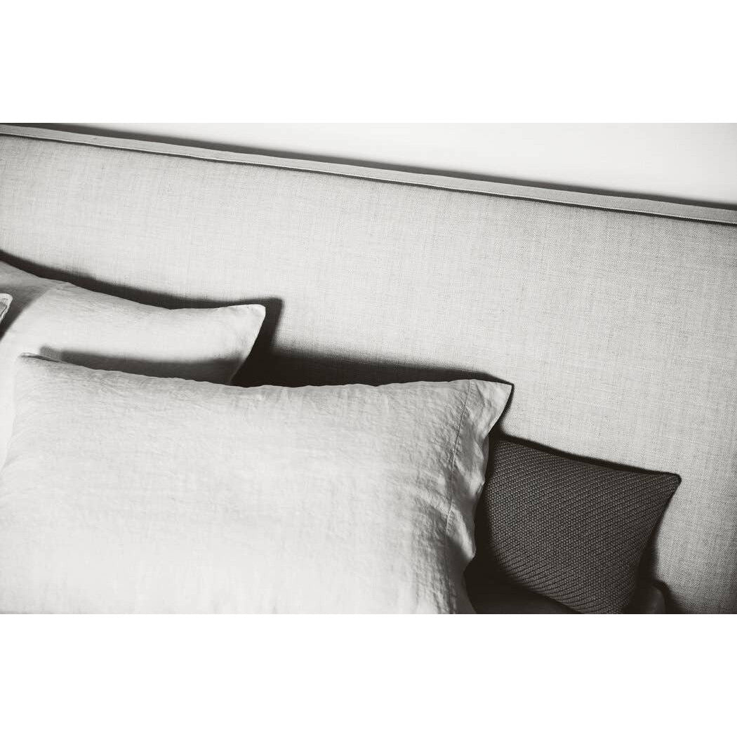 Close-up of the Richard Bed's textured headboard fabric and white linen pillows, emphasizing high-end tailoring details.