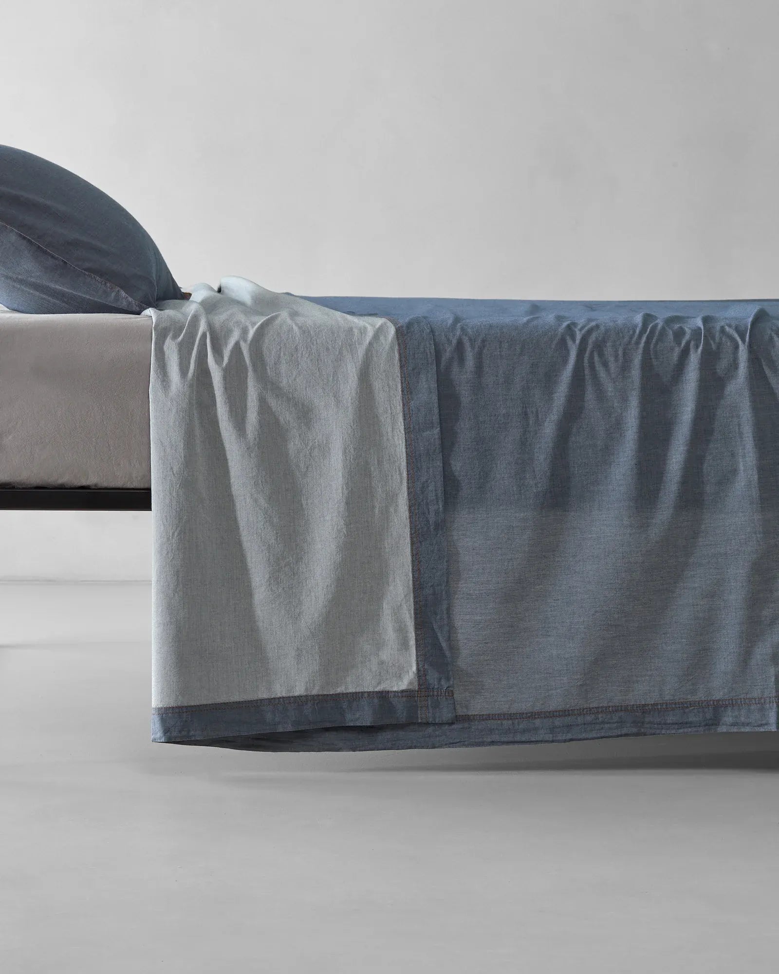 Society Limonta Nim bed sheet and pillowcase styled on a bed, featuring a casual luxury look with garment-dyed Italian cotton.